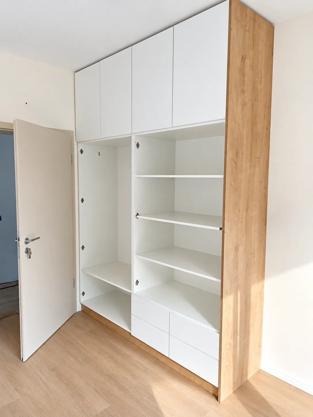 Ruhásszekrény fehér belső kialakítása polcokkal, akasztós rekesszel és alsó fiókokkal, tölgyhatású oldallappal.